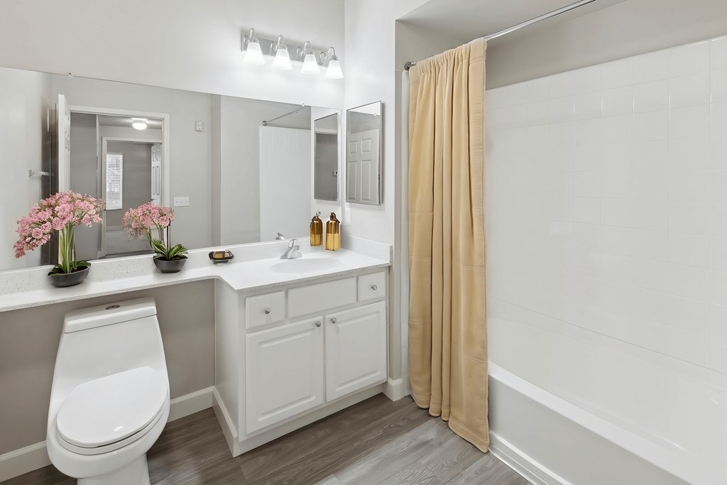 A white bathroom with a toilet, sink, and mirror.