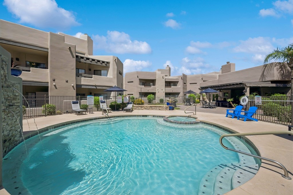 A swimming pool in front of a building with a blue sky in the background.