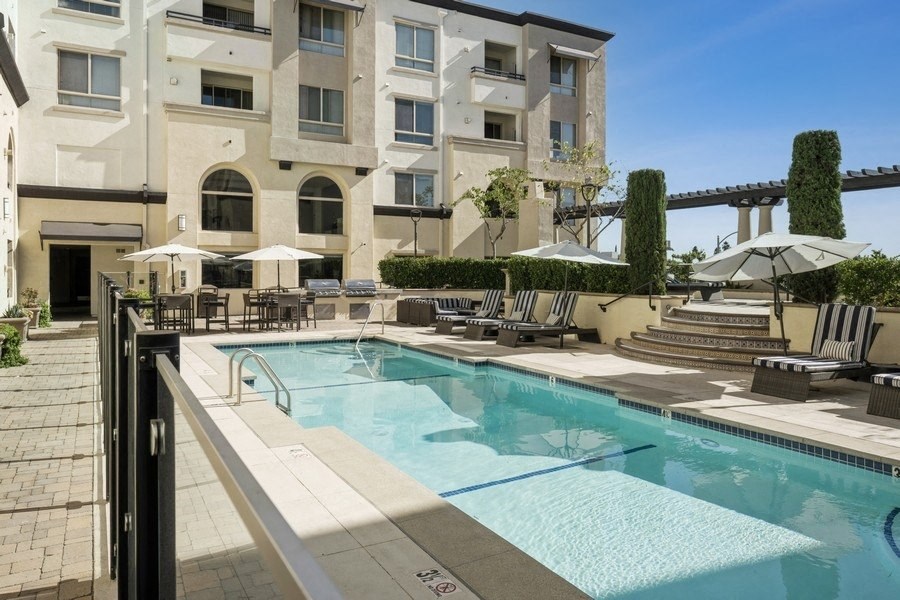 a swimming pool with chairs and umbrellas in front of a building