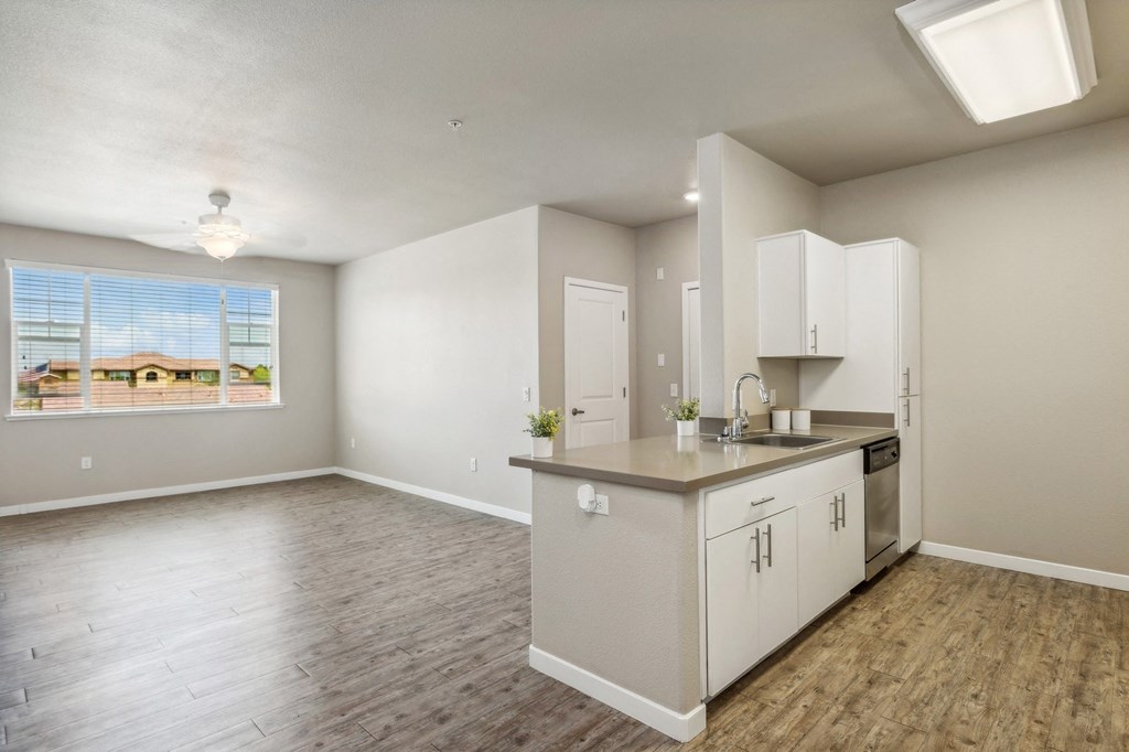 an empty kitchen and living room with white cabinets and a window