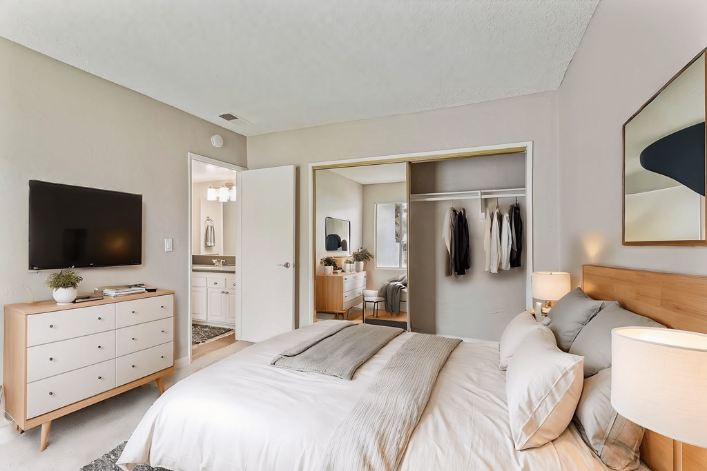 A bedroom with a large bed and a dresser with a flat screen TV on top.