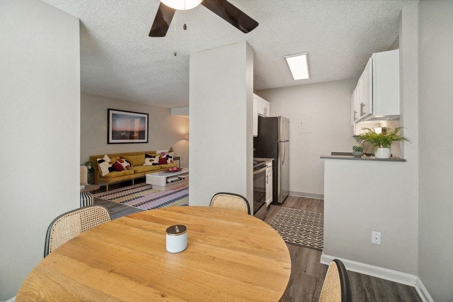 a dining room with a wooden table and a kitchen in the background