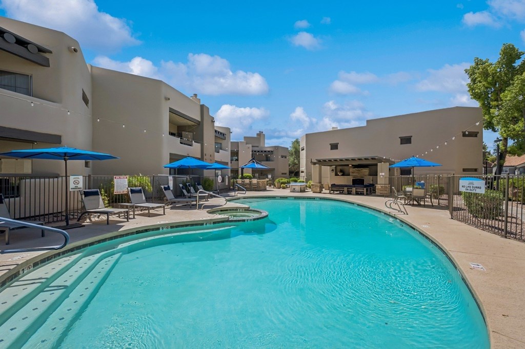A large swimming pool in front of a building with a fence around it.