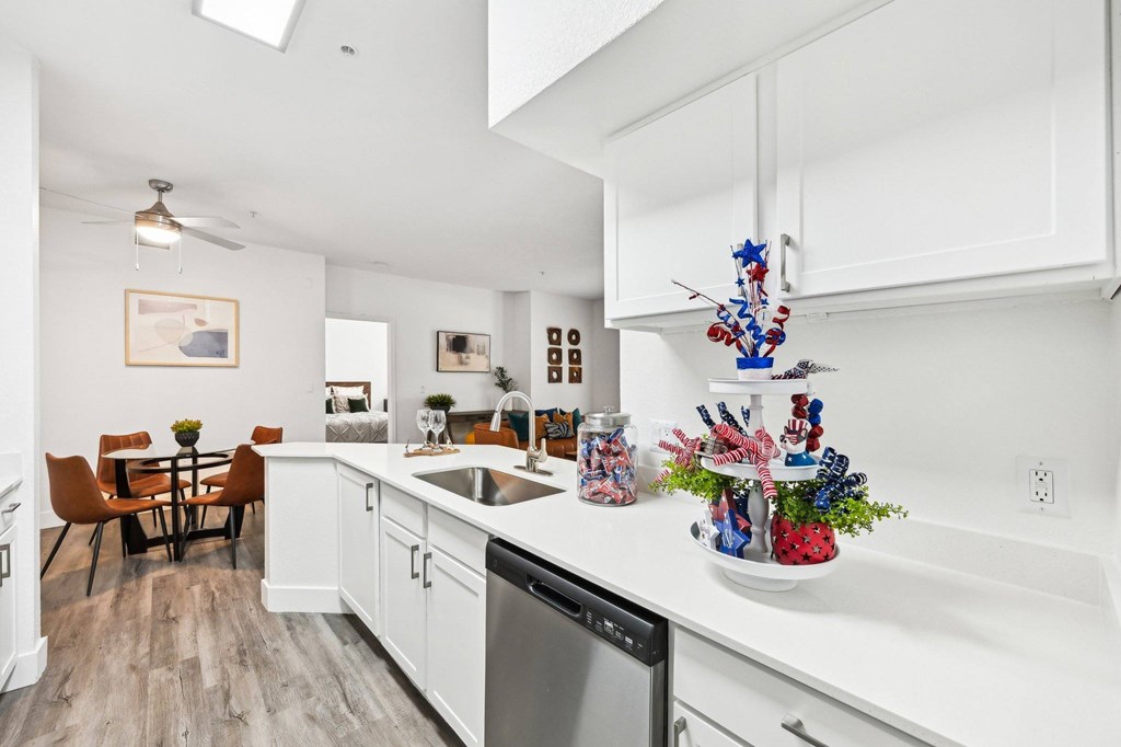 A kitchen with white cabinets and a wooden floor.