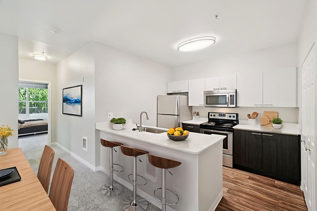 A modern kitchen with a white island and black cabinets.