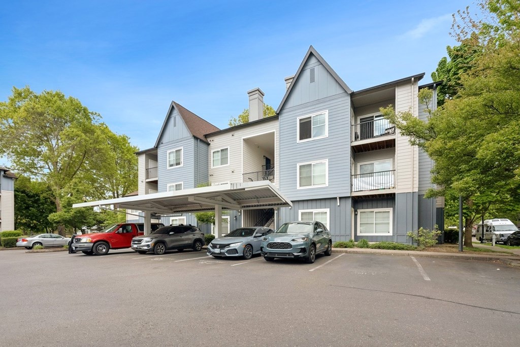 A grey apartment building with cars parked in front.