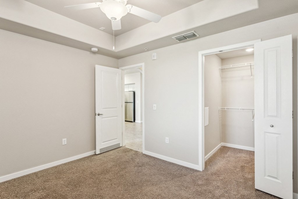 an empty bedroom with a closet and a ceiling fan