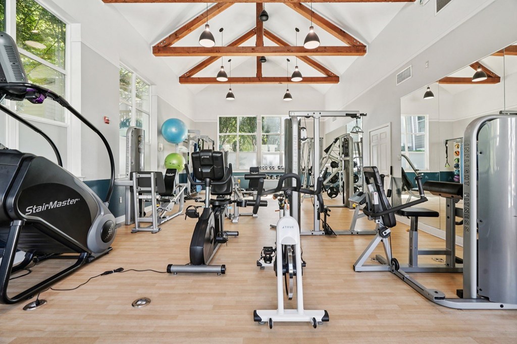 A gym with a variety of equipment including treadmills, stationary bikes, and weight machines.