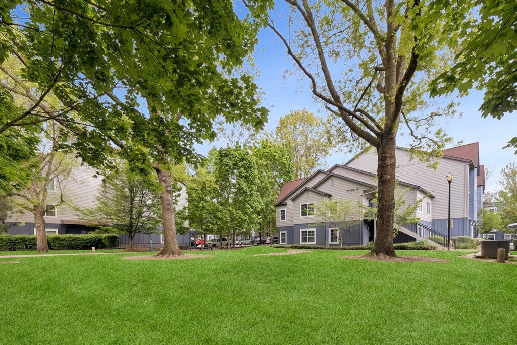 A large grassy area with trees and a building in the background.