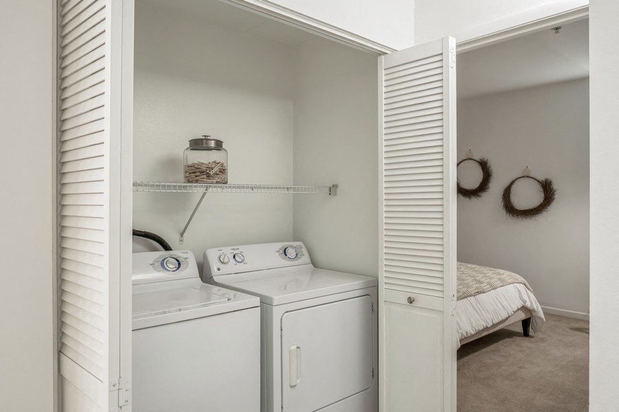 a laundry room with a washer and dryer and a bed