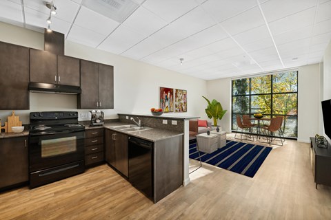 a kitchen and living room with dark cabinets and a large window