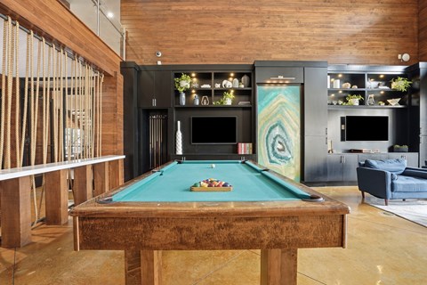 A pool table in a room with a wooden floor and a fireplace.