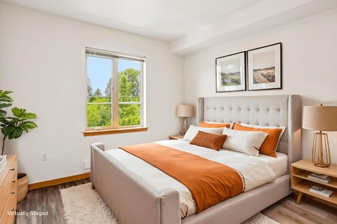 A bedroom with a large bed and a window overlooking a green landscape.