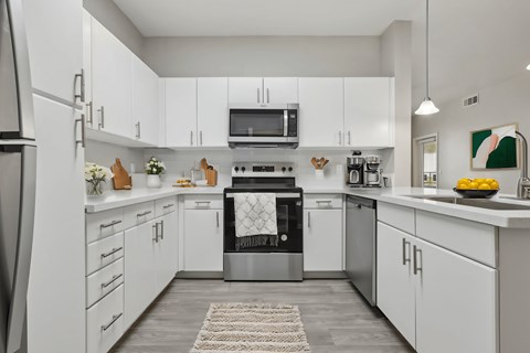 A modern kitchen with white cabinets and stainless steel appliances.