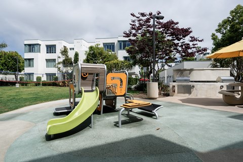 A playground with a yellow slide and a green slide.