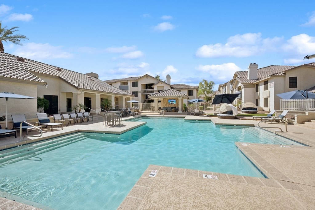 A large swimming pool surrounded by lounge chairs and umbrellas.