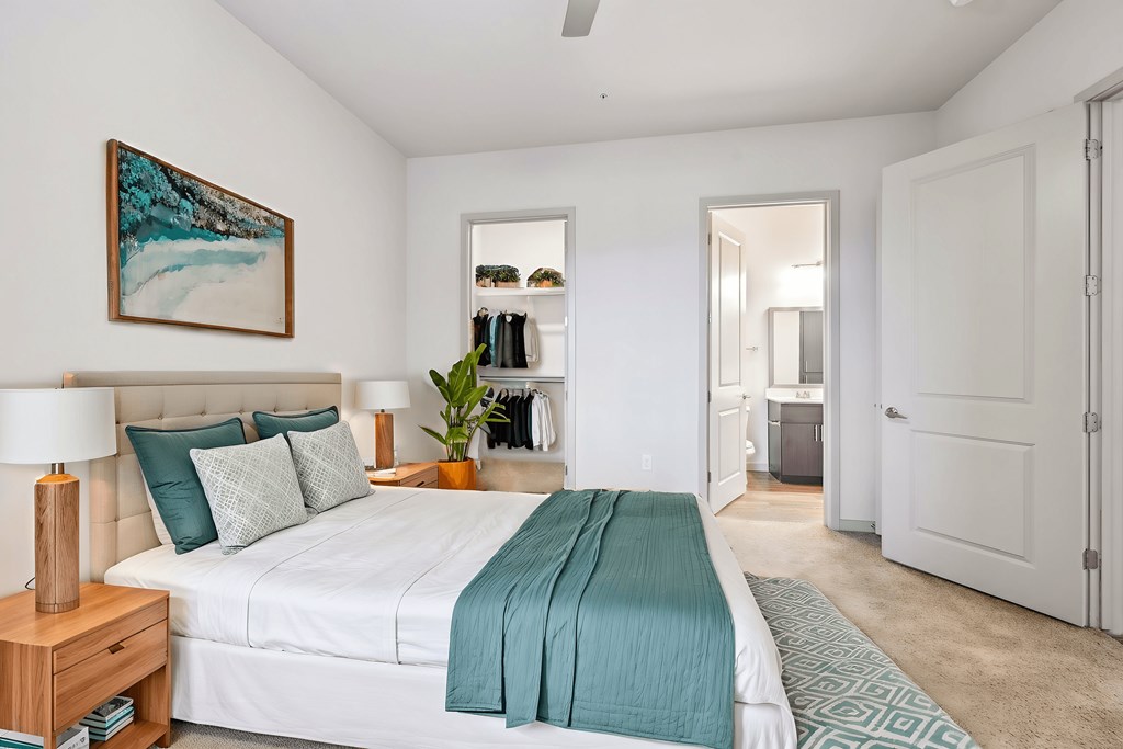 A bedroom with a large bed and a painting on the wall.