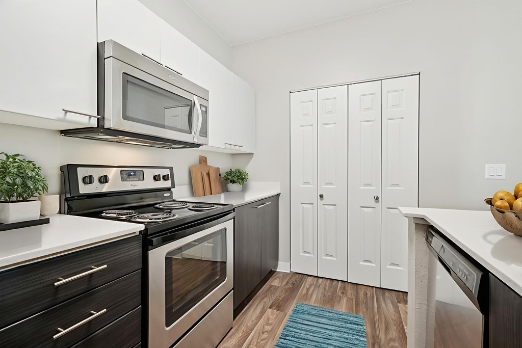A modern kitchen with a black stove top oven and a silver microwave above it.