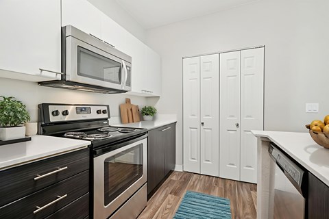 A modern kitchen with a black stove top oven and a silver microwave above it.