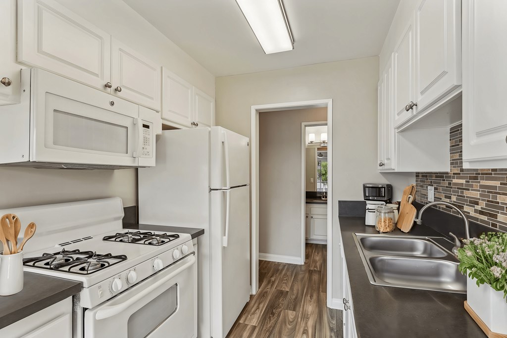 A kitchen with white cabinets and a brick backsplash.