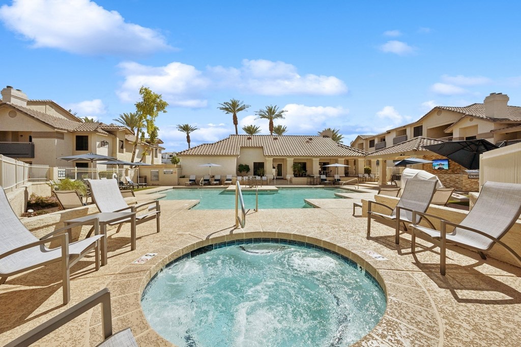 A  spa surrounded by lounge chairs in a sunny outdoor setting.