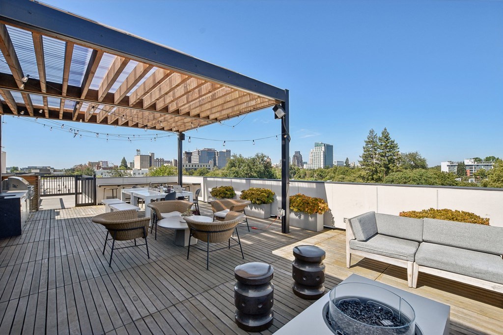 a rooftop patio with tables and chairs and a city in the background
