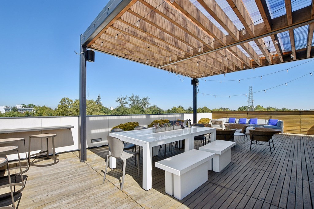 a rooftop patio with a table and chairs and a pergola