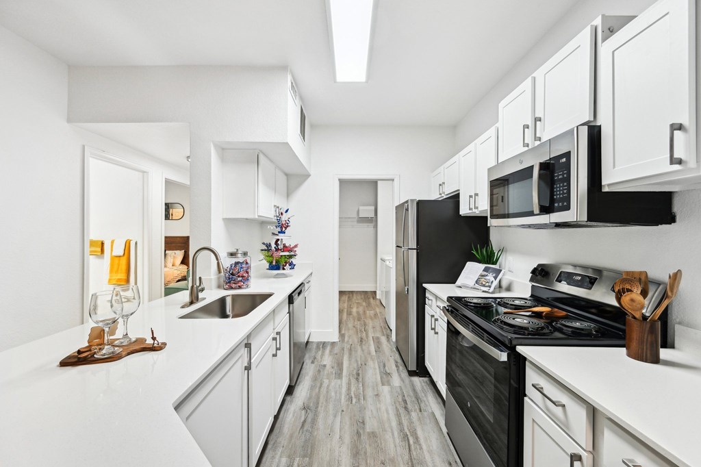 A kitchen with black appliances and white cabinets.