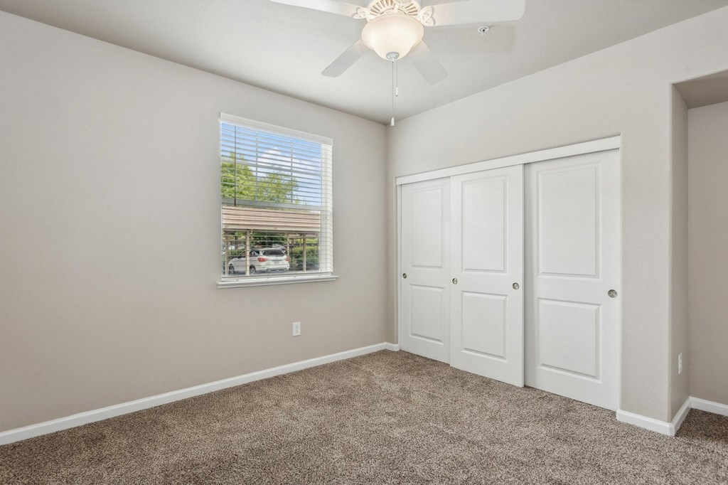 an empty bedroom with carpet and a ceiling fan