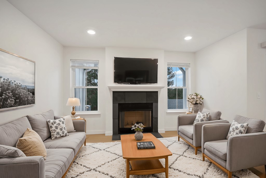 A living room with a grey couch, a coffee table, a fireplace, and a painting on the wall.