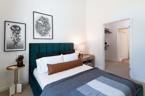 A bedroom with a bed, nightstand, and two pictures on the wall.