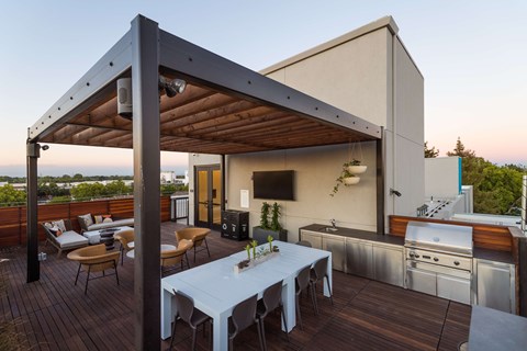 A modern outdoor kitchen with a dining table and chairs.