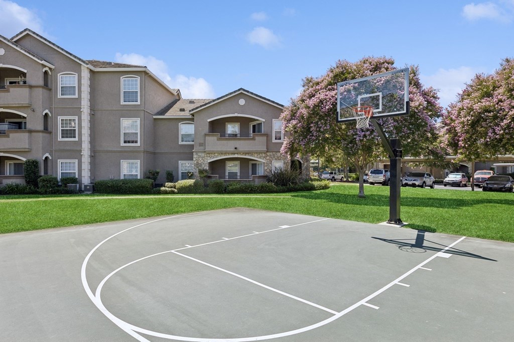 an outdoor basketball court in front of an apartment building