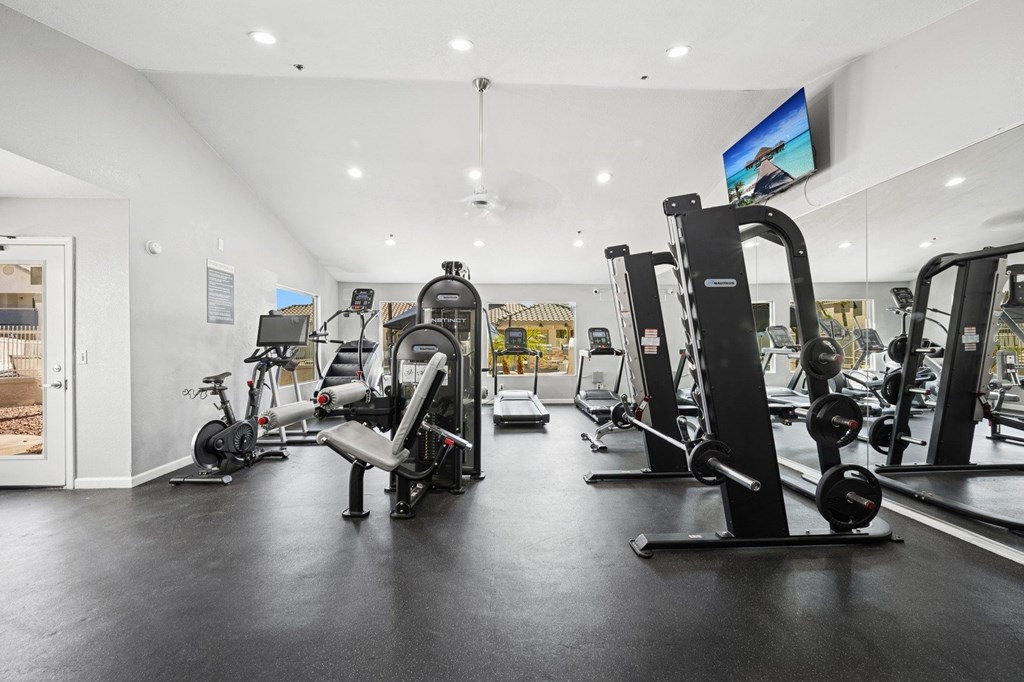 A gym with a variety of equipment including treadmills, weights, and exercise machines.