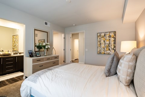 A bedroom with a large bed and a vanity with a mirror.