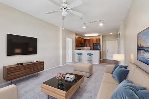 A living room with a brown coffee table and a flat screen TV mounted on the wall.