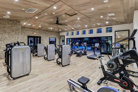 A gym with a variety of exercise equipment including treadmills, stationary bikes, and weight machines.