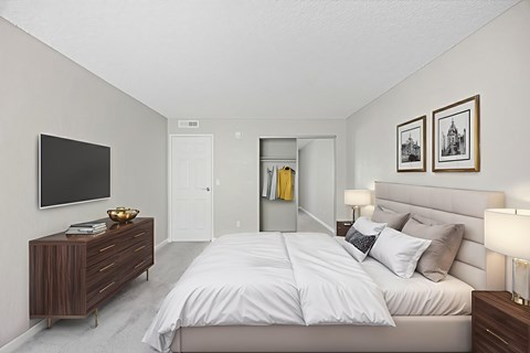 A bedroom with a large bed and a TV on the wall.