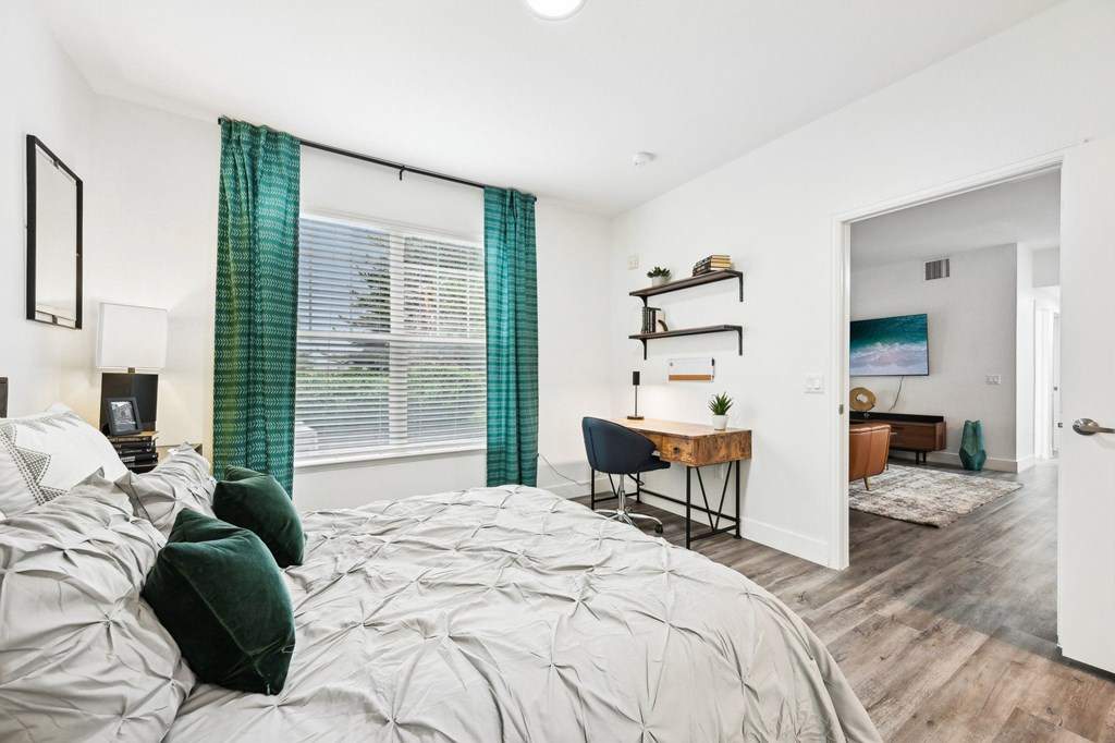 A bedroom with a large bed and a desk with a chair.
