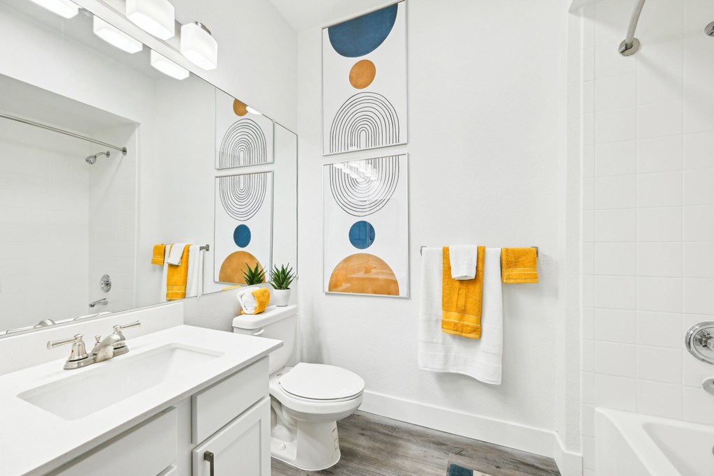 A bathroom with a white toilet, sink, and a white tub.