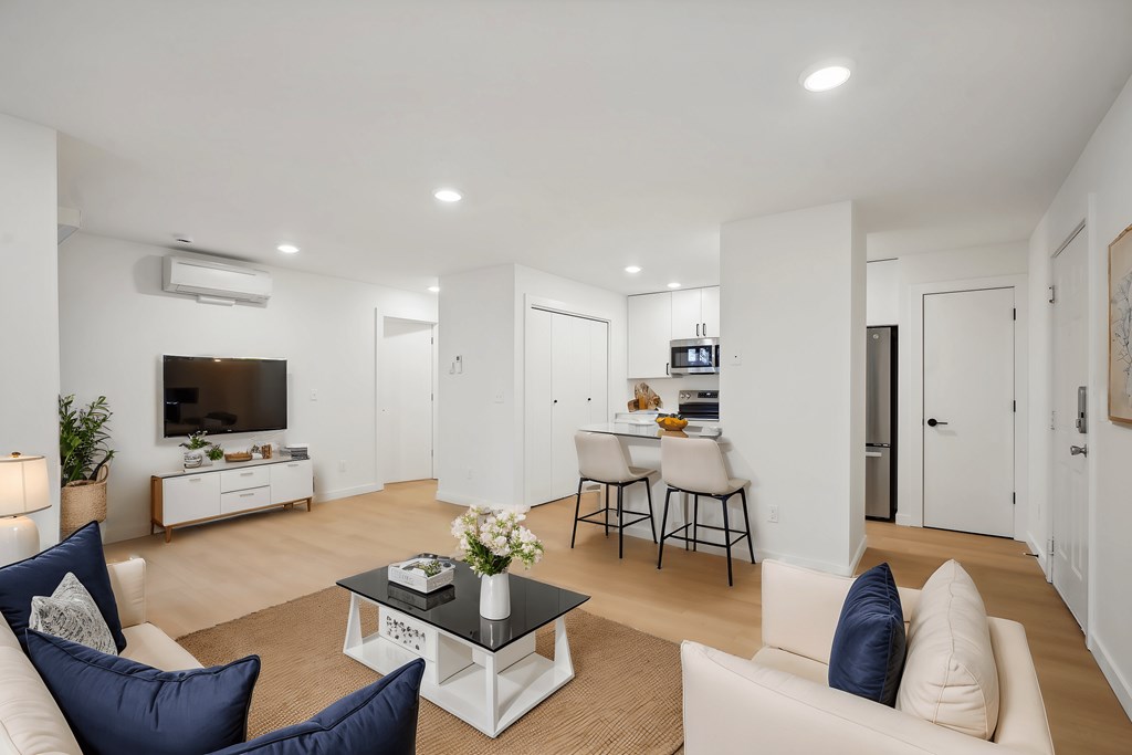 A living room with a white couch, a black coffee table, and a television.