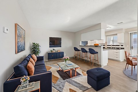 A living room with a dark blue couch and a coffee table with a vase of flowers on it.