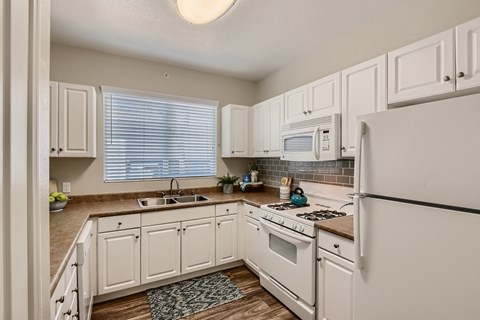 a kitchen with white cabinets and appliances and a white refrigerator