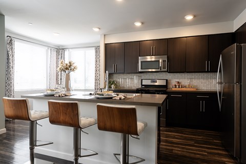 A modern kitchen with dark brown cabinets and a white island.