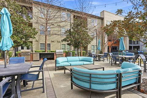 A patio with a table, chairs, and umbrellas.