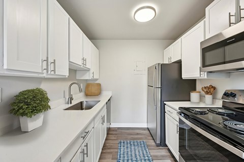 A kitchen with white cabinets and a black refrigerator.