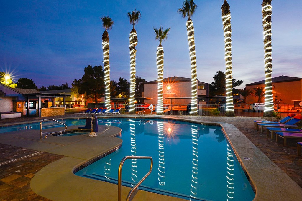 a swimming pool at night with palm trees in the background