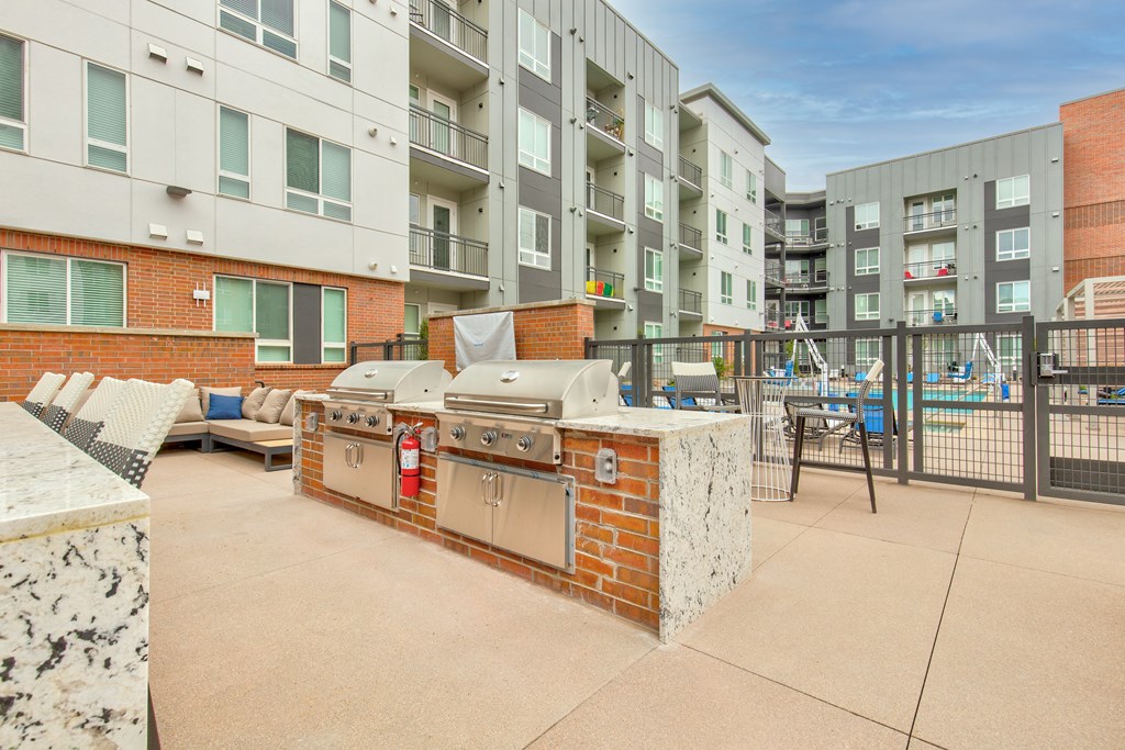 an outdoor patio with a barbecue grill and a pool in front of an apartment building