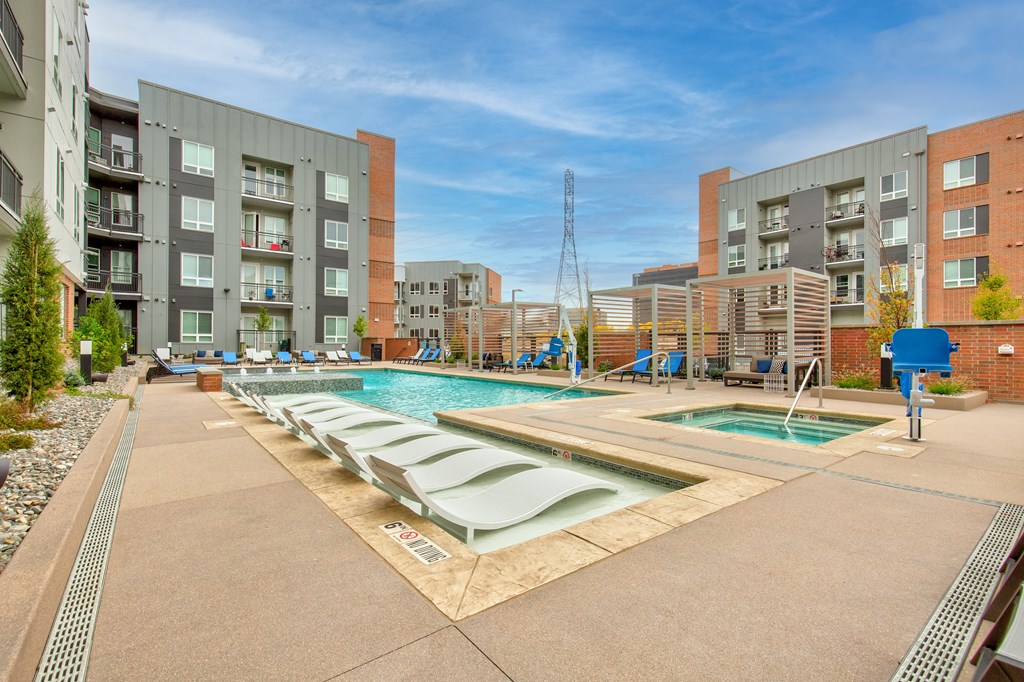 a swimming pool with chaise lounge chairs in front of an apartment building