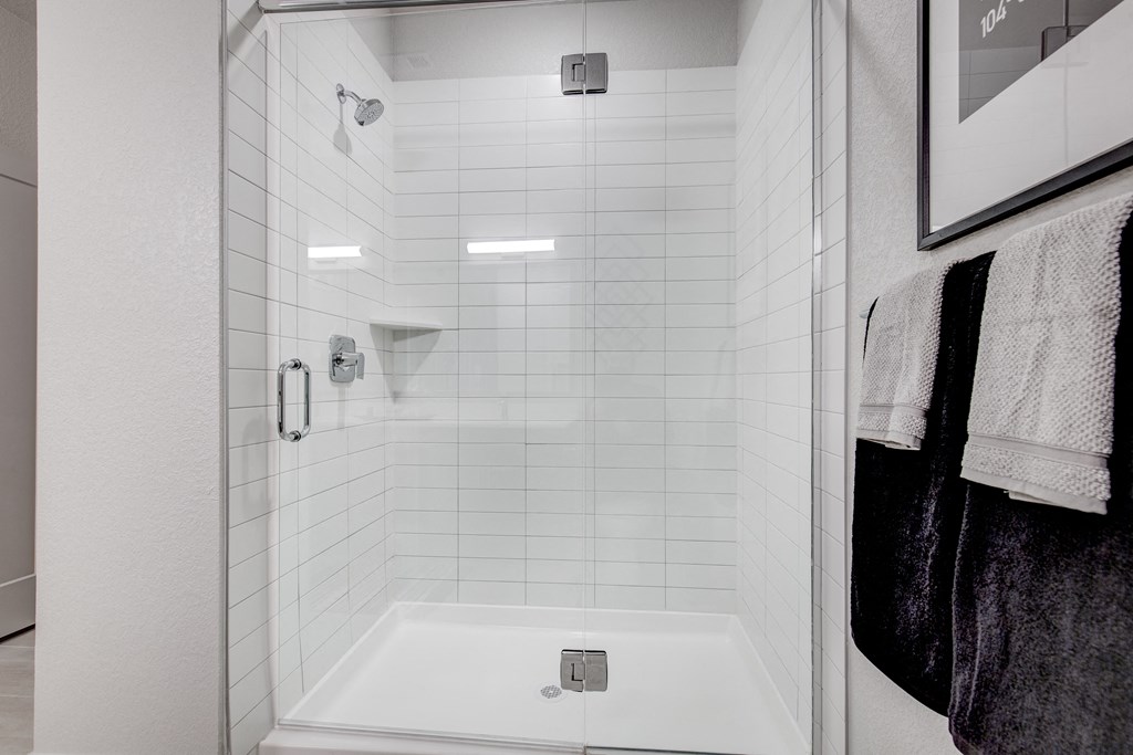 a white shower with white tiles in a bathroom